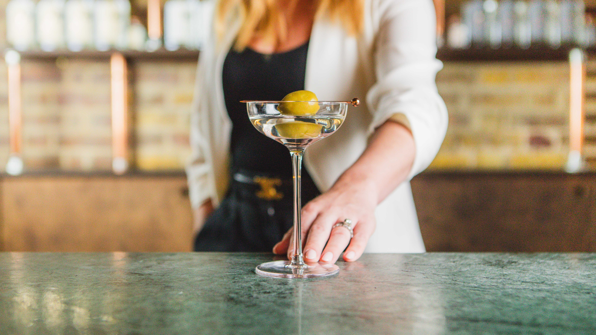 Carmen O'Neal sliding a martini forward on a bar